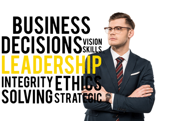 apuesto hombre de negocios de pie con los brazos cruzados cerca de decisiones empresariales habilidades de visión liderazgo integridad ética resolución de letras estratégicas en blanco
  - Foto, Imagen