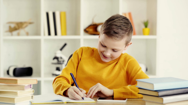 陽気な子供がノートに書き込み、笑顔で自宅で親指を見せる  - 映像、動画