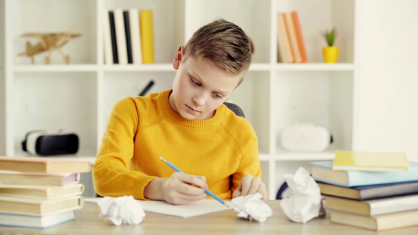 displease school jongen tekenen op papier, verkruimeld papier, gooien in de lucht terwijl zittend in de buurt van boeken thuis  - Video