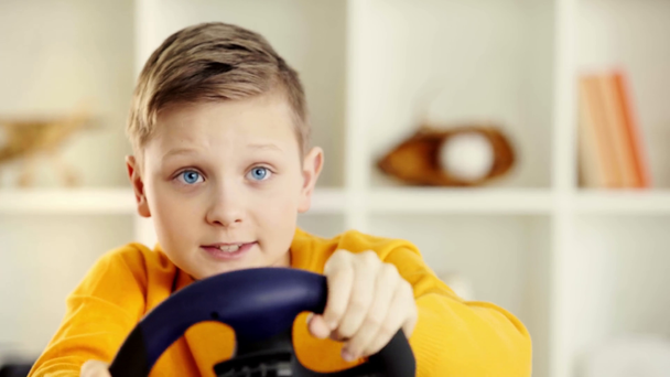 selektivní zaměření dětské přidržením volantu na hraní a hraní videohry doma - Záběry, video