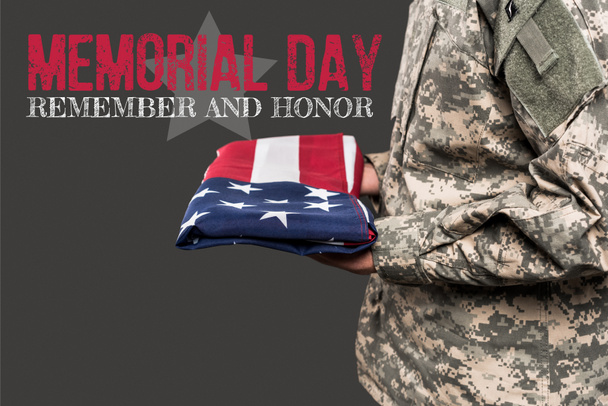κομμένη θέα του ανθρώπου σε στρατιωτική ομοιόμορφη κατοχή σημαία της Αμερικής κοντά στην ημέρα μνημείου γράμματα σε γκρι  - Φωτογραφία, εικόνα