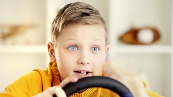 selektivní zaměření emocionálního dítěte přidržující volant a oslavovat triumf po přehrání videohry - Záběry, video