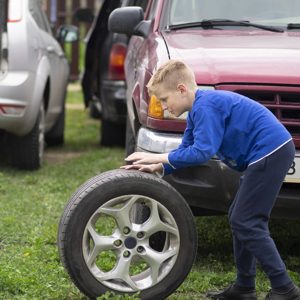 caucasian boy is rolling a car wheel - Photo, Image