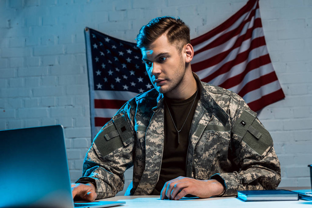 handsome military man in uniform sitting in office and using laptop  - Foto, imagen