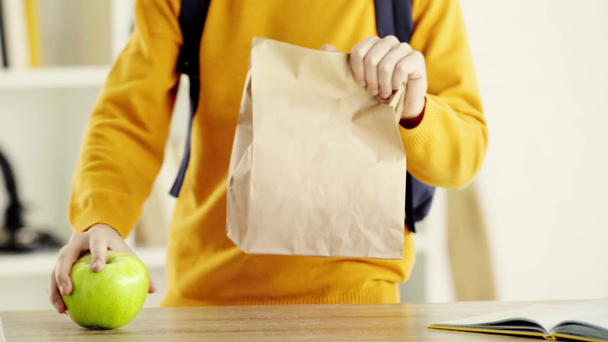 περικομμένη θέα του παιδιού περπάτημα και λαμβάνοντας νόστιμο μήλο και χάρτινη σακούλα στο σπίτι  - Πλάνα, βίντεο