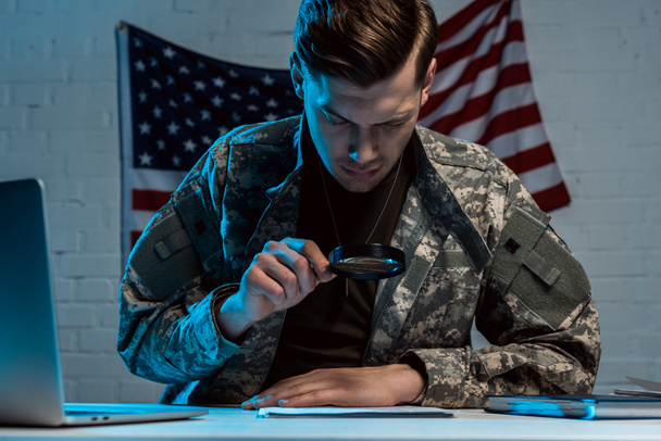 soldier holding magnifying glass while reading document in office  - Photo, Image