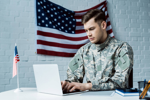 młody żołnierz w mundurze za pomocą laptopa w biurze  - Zdjęcie, obraz