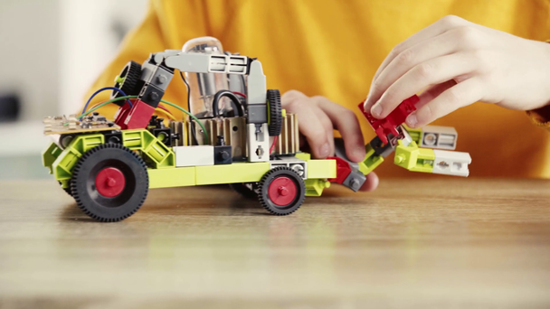 cropped view of child playing with electric car made of building blocks near books on table - Footage, Video