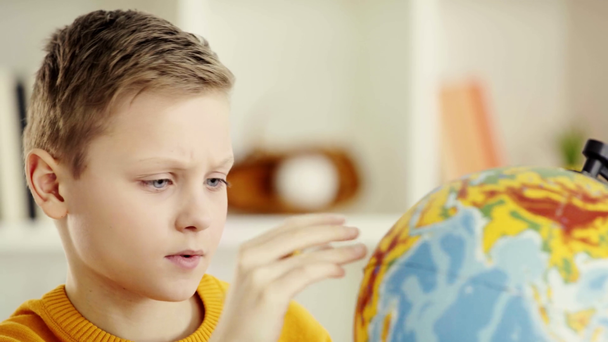 school jongen kijkend naar Globe, zoeken, wijzend met de vinger en glimlachend thuis  - Video