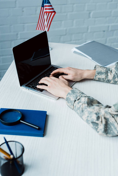 cropped view of military man typing on laptop with blank screen  - 写真・画像