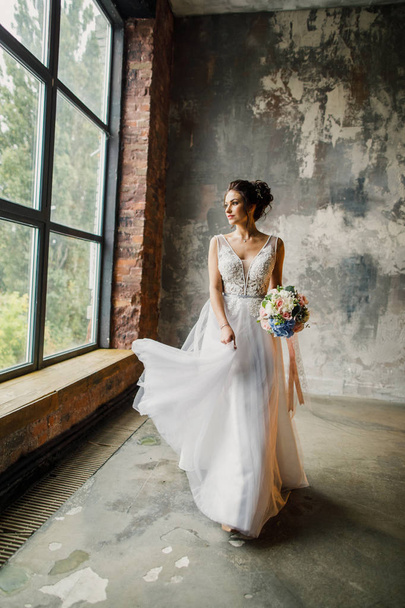 portrait of a young beautiful wedding bride in a beautiful stylish dress on a gray background - Valokuva, kuva