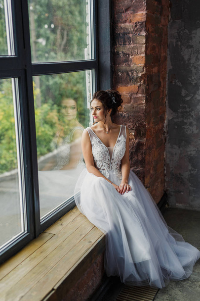 portrait of a young beautiful wedding bride in a beautiful stylish dress on a gray background - Фото, зображення