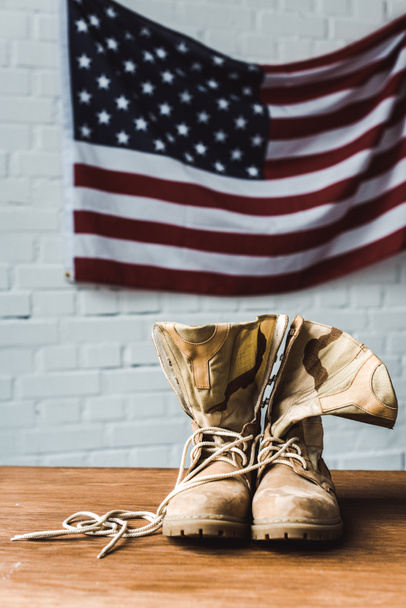 military boots near american flag with stars and stripes on brick wall  - Фото, изображение