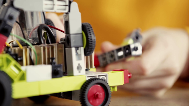 cropped view of schoolboy playing with electric car made of building blocks on table  - Footage, Video