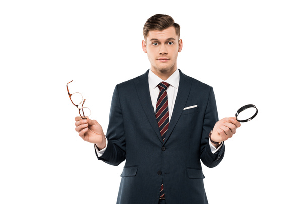 surprised businessman holding glasses and magnifying glass isolated on white  - Фото, зображення