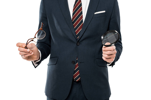 cropped view of businessman holding glasses and magnifying glass isolated on white  - Foto, Imagem