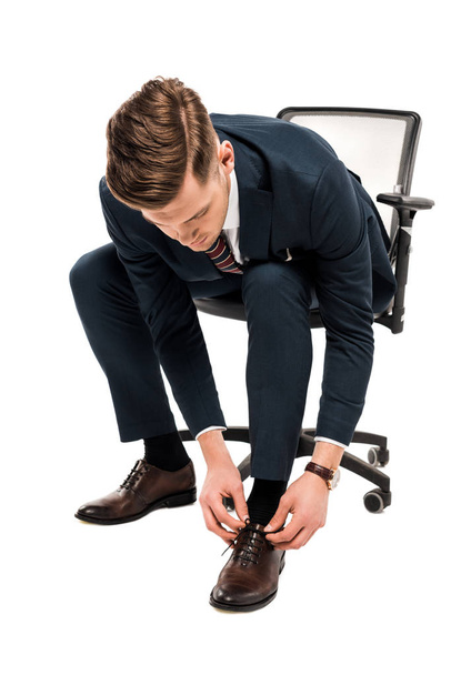 handsome businessman in suit tying shoelaces isolated on white  - Φωτογραφία, εικόνα
