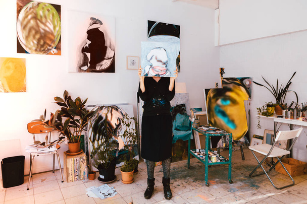 muotokuva naistaiteilija poseeraa työpajassa piilossa kasvot maalaus
 - Valokuva, kuva