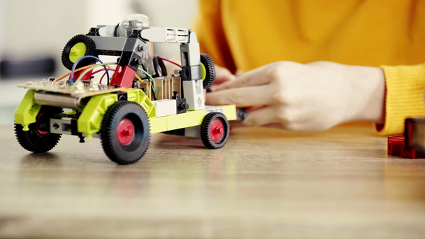 обрізаний вид дитини грає з електричним автомобілем з будівельних блоків на столі біля книжок - Кадри, відео