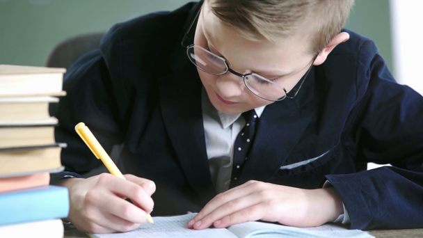 selective focus of cheerful child in glasses writing near books  - Video, Çekim