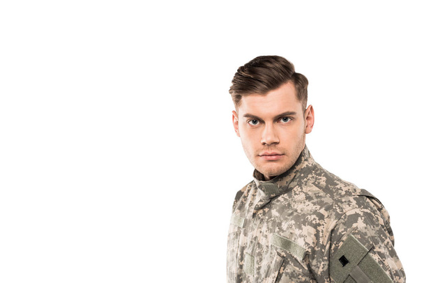 soldado sério e bonito em uniforme olhando para a câmera isolada no branco
  - Foto, Imagem