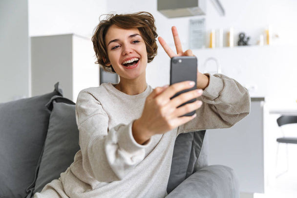 Smiling brunette woman making selfie on smartphone - 写真・画像