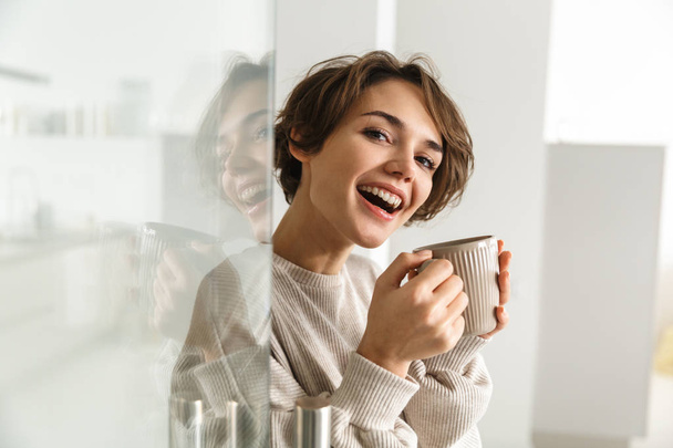 Side view of Happy brunette woman drinking coffee - Foto, afbeelding