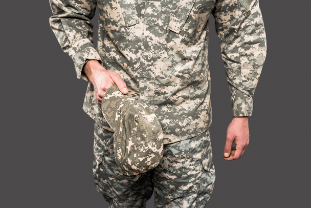 cropped view of soldier holding cap isolated on grey  - Фото, зображення