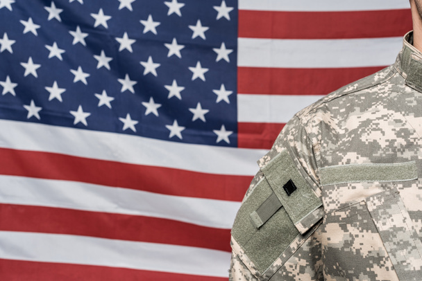 cropped view of soldier in military uniform near flag of america - Фото, изображение