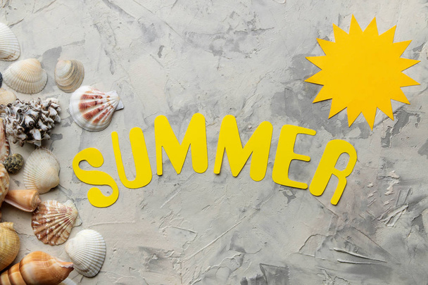 The word summer of paper yellow letters and sea accessories, shells on a light concrete background. summer. vacation. relaxation. top view. - Foto, Bild