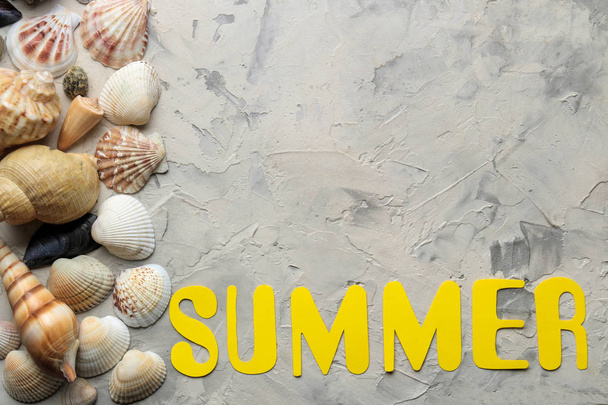 La palabra verano de papel amarillo letras y accesorios de mar, conchas sobre un fondo de hormigón ligero. Verano. vacaciones. Relajación. Vista superior. espacio para texto
 - Foto, imagen