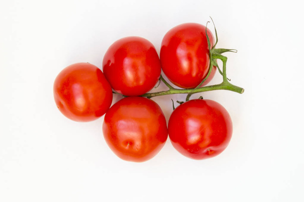 Organic red tomatoes with a green twig handful, lie on a white background. There is a place for text. - Photo, image