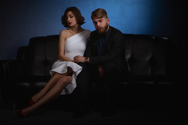 sad man and woman sitting on the couch. the man looks forward and the woman looks away from him. - Fotografie, Obrázek