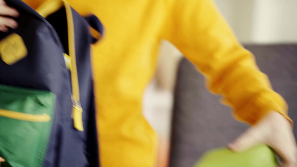 cropped view of schoolboy opening backpack and putting book, notebook, lunch box and green apple  - Footage, Video