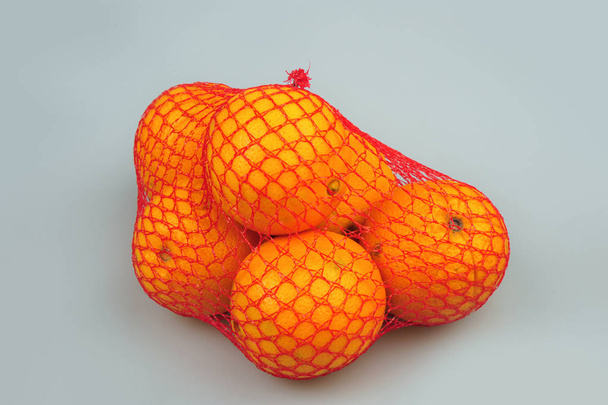 Fresh oranges in mesh isolated on the gray background - Фото, зображення