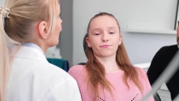 Οδοντίατρος που μιλάει με έφηβο κορίτσι και τον πατέρα της στην κλινική του οδοντιάτρου - Πλάνα, βίντεο