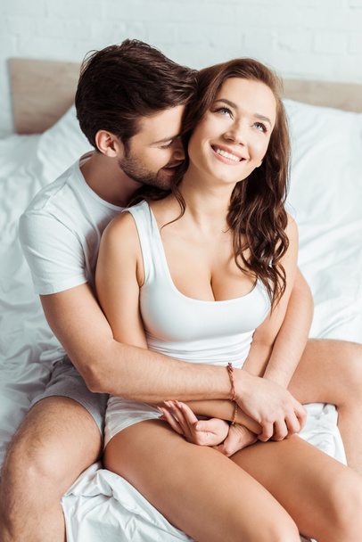 handsome man hugging happy girlfriend in bedroom  - 写真・画像
