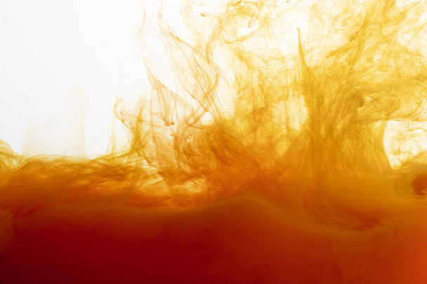 Close up view of orange paint swirls in water - Foto, imagen