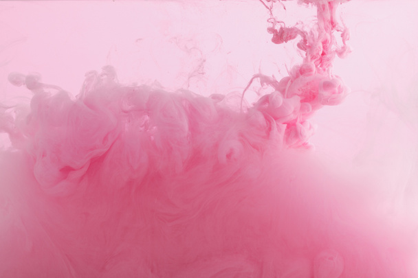 Vista de cerca de los remolinos de pintura rosa mezclándose en agua
   - Foto, Imagen