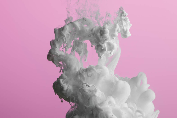 Close up view of white paint splash isolated on pink - 写真・画像