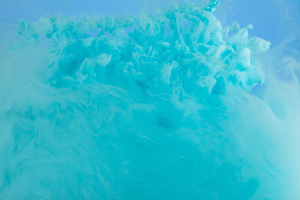 Close up view of turquoise smoky paint swirls isolated on blue - Photo, Image