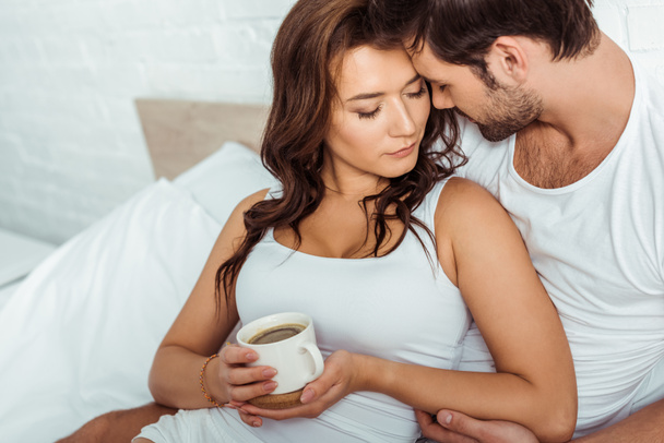 bel homme près de femme attrayante tenant tasse de café au lit
  - Photo, image