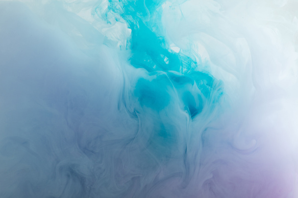 Close-up van blauwe en paarse rokerige verf dwarrelt in het water  - Foto, afbeelding