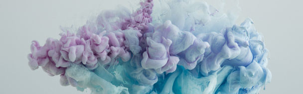 Close-up van licht blauwe, roze en paarse verf dwarrelt in het water - Foto, afbeelding