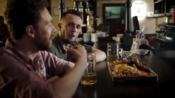 Vidám barátok iszik csapolt sör és étkezési snack-ban egy pub - Felvétel, videó