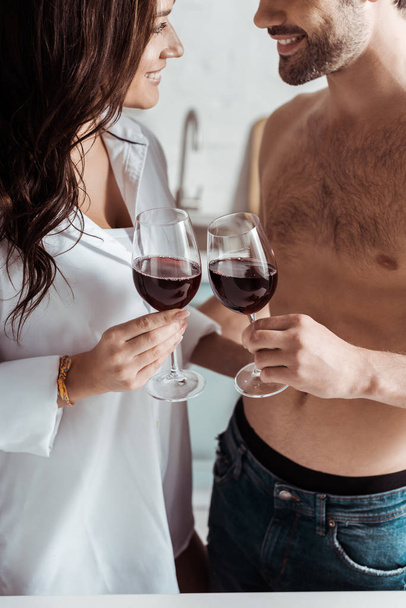 cropped view of cheerful muscular man holding wine glass near attractive girl at home  - Foto, Imagem