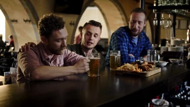 fröhliche Freunde, die Bier vom Fass trinken und Snacks in einer Kneipe essen - Filmmaterial, Video
