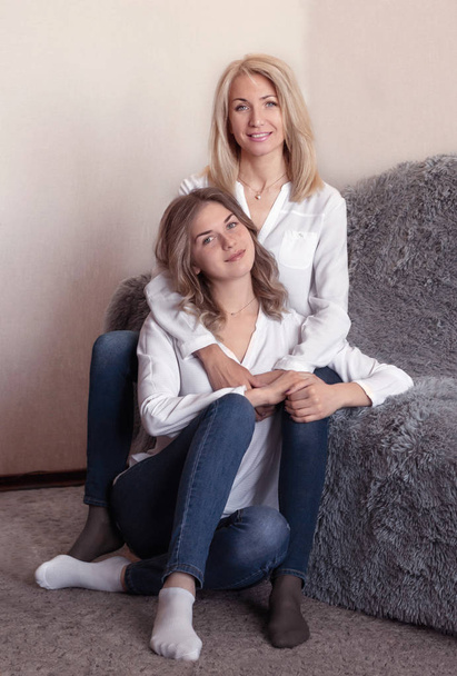 Beautiful senior mom and her adult daughter are hugging, looking at camera and smiling - Foto, Bild