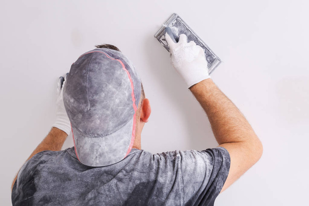 Plasterer polishing a gypsum wall. House renovation concept. - Фото, изображение