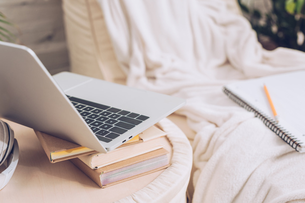 selective focus of laptop and books near soft white chaise lounge covered with white blanket  - Foto, Imagem